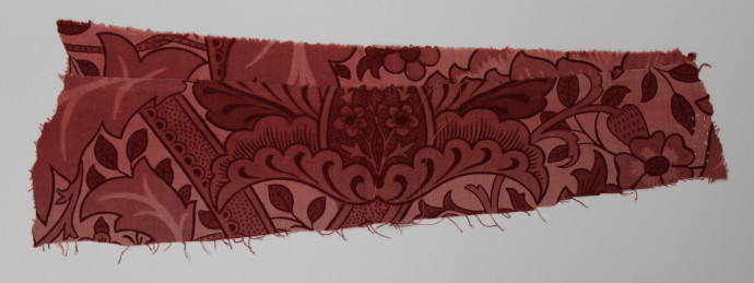 Fabric fragment featuring twisted stems and large elaborate flowers in shades of red.