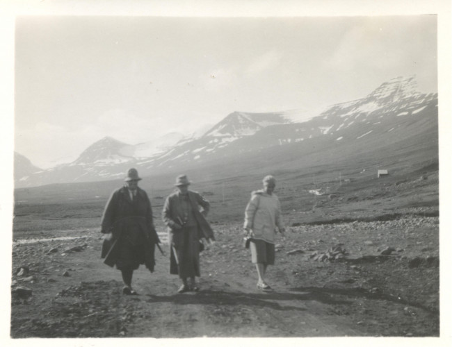 A black and white photograph of three women in hiking clothes with mountains in the background.