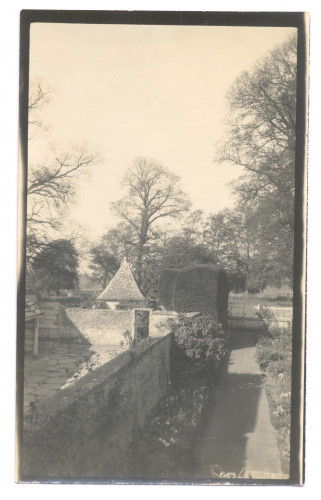 A sepia photograph showing an old courtyard with plants, shrubs and trees