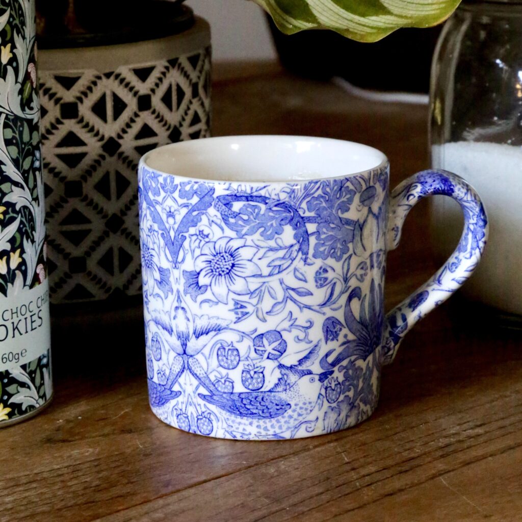 Blue and white ceramic mug with a strawberry thief bird pattern