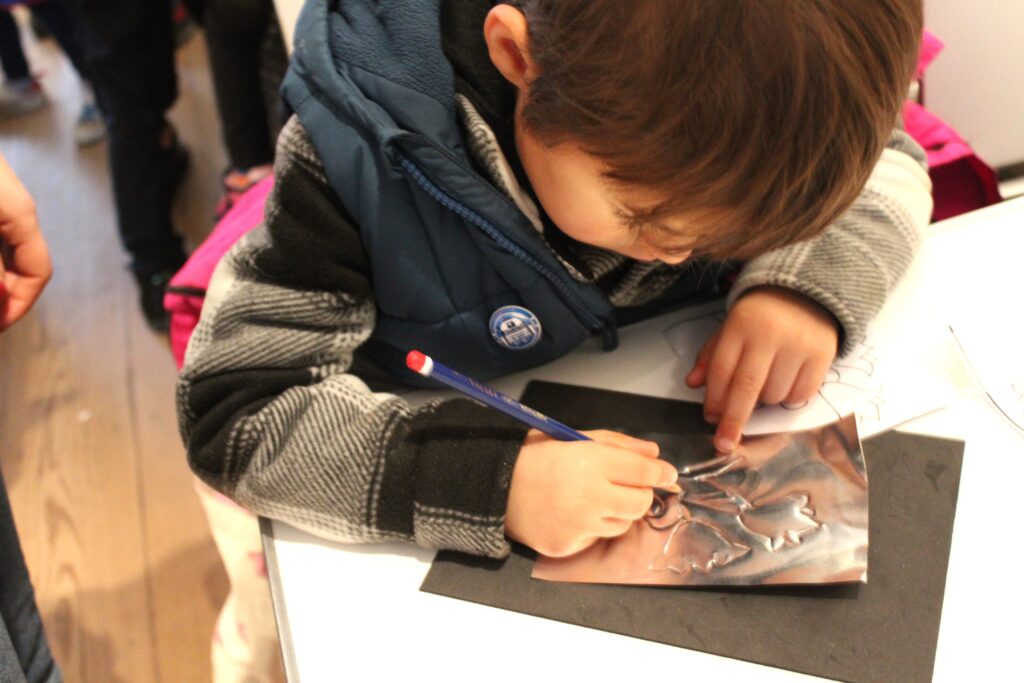 Child completing a craft activity - embossing a pattern onto metal